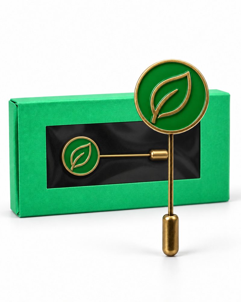 Green enamel leaf pin with a brass stick pin, shown with its green gift box