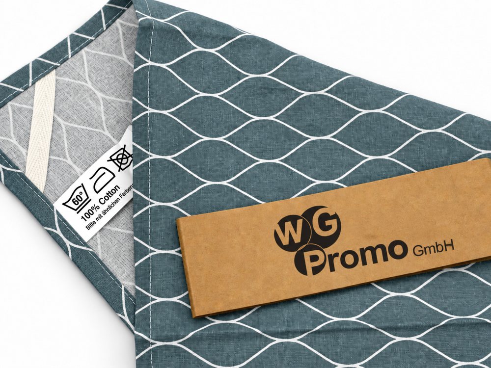 Teal patterned tea towel with a kraft paper band printed with the WG Promo logo
